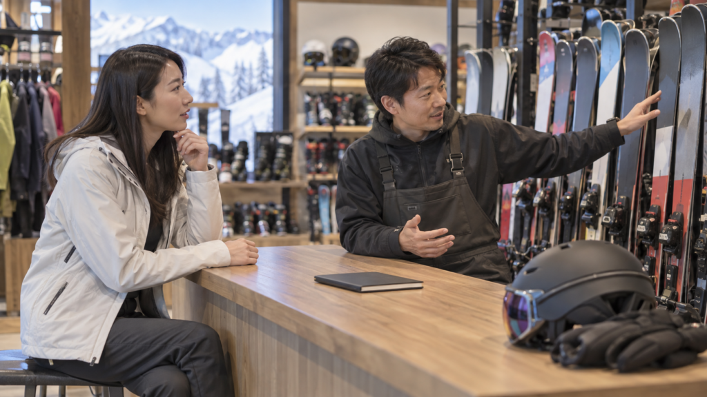 店舗スタッフとスキー板の候補を相談する成人女性