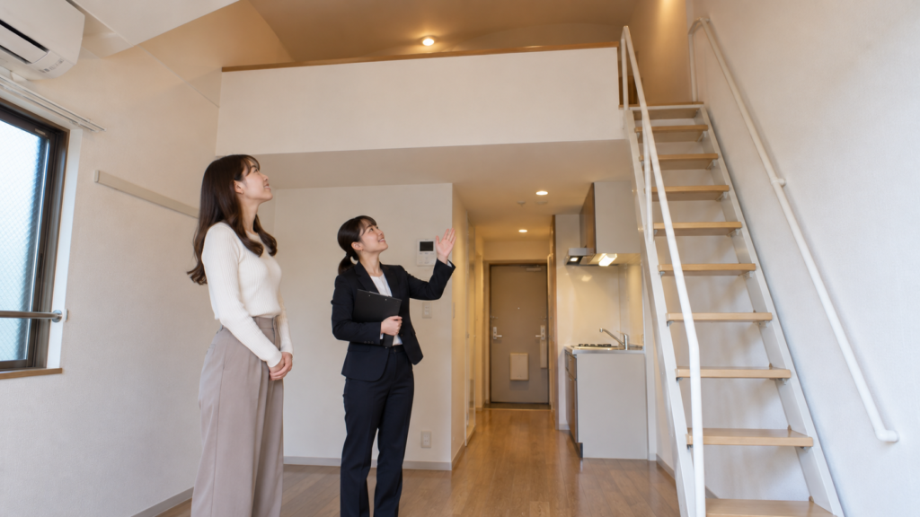 日本の賃貸住居のロフト入口と固定階段を下から確認する女性のイメージ